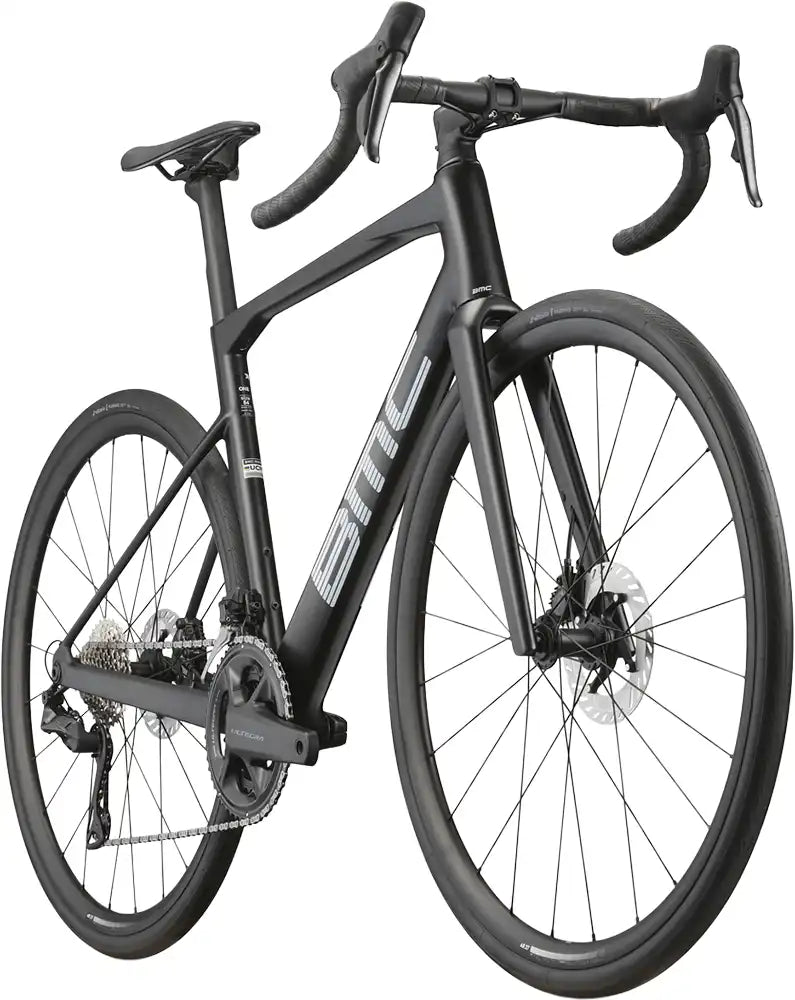Red BMC Roadmachine ONE road bike with aerodynamic frame and drop handlebars, ready for high-performance cycling.