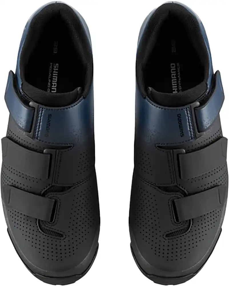 Shimano XC102 women's mountain bike shoes showing black and pink design with Velcro straps and rugged sole.