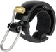 Black Knog Oi Luxe Bell attached to a bicycle handlebar, showcasing its sleek design and compact size as a stylish bike accessory.